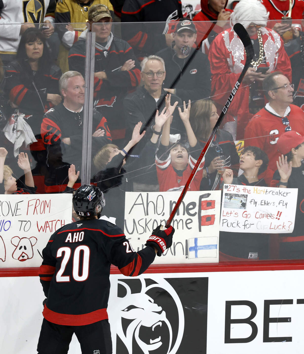Carolina's Sebastian Aho (20) drops a puck to a young fan as they warm up before their game against the Golden Knights in the second game of the Stanley Cup Final at the Lenovo Center in Raleigh, N.C., Thursday, June 4, 2026.