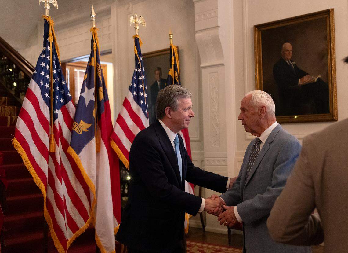Gov. Roy Cooper shakes hands with former North Carolina basketball coach Roy Williams following a ceremony during which Williams was awarded The Order of the Long Leaf Pine at the Executive Mansion on Thursday, Dec. 19, 2024, in Raleigh, N.C.