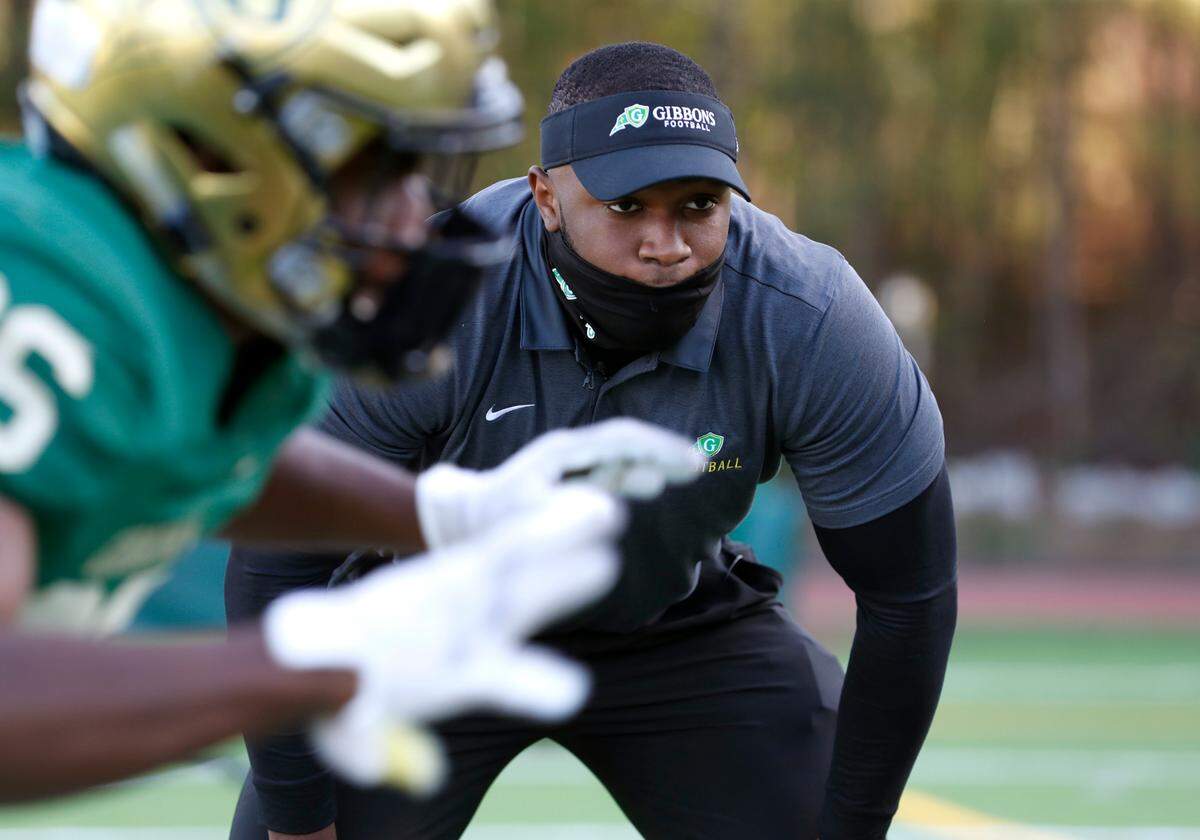 N.C. State linebacker Isaiah Moore watches as Cardinal Gibbons High School football players run drills before the Crusaders’ game against Pine Forest in Raleigh, N.C., Friday, April 16, 2021. Moore is doing a minor at State in coaching. Part of the curriculum required a certain amount of intern hours getting real life coaching experience, which led Moore to volunteer coach at Gibbons this season.