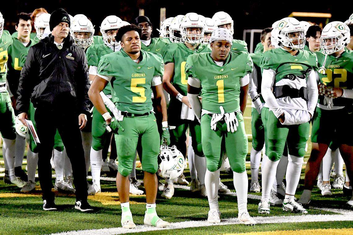 Cardinal Gibbons’ Kendall Scotton (5), Corban McDaniel (1) and teammates look on as the East Regional Championship trophy is presented to Rolesville.