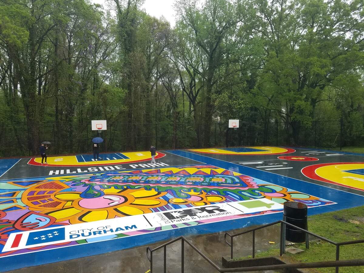 Former Duke and NBA player Grant Hill (center, with blue umbrella) walks around the renovated basketball courts at Durham’s Hillside Park on Saturday, April 13, 2019. Hill’s charitable foundation teamed with sporting goods company Fila to fund the renovations.