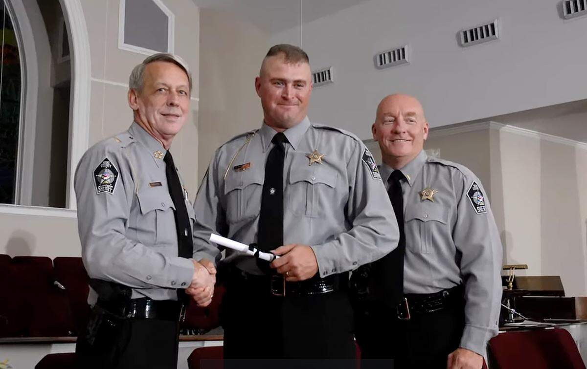 Roy Woodlief, center, poses with Wake County Sheriff Donnie Harrison and Terry Putnam after Woodlief graduated the academy and became a sheriff’s deputy.