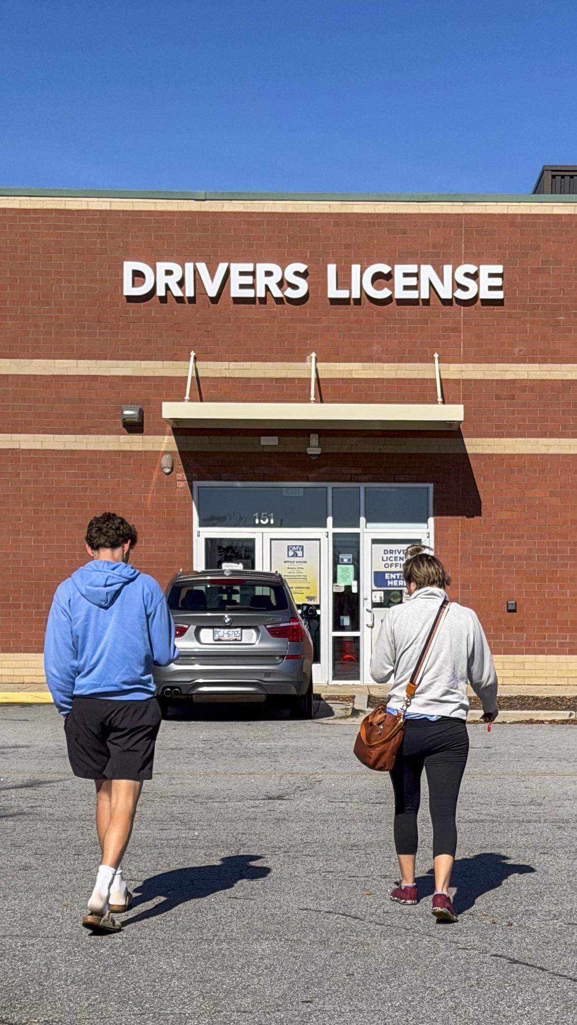 People walk towards a N.C. Division of Motor Vehicles office on New Bern Avenue in Raleigh around noon on Tuesday, Nov. 4, 2025. 