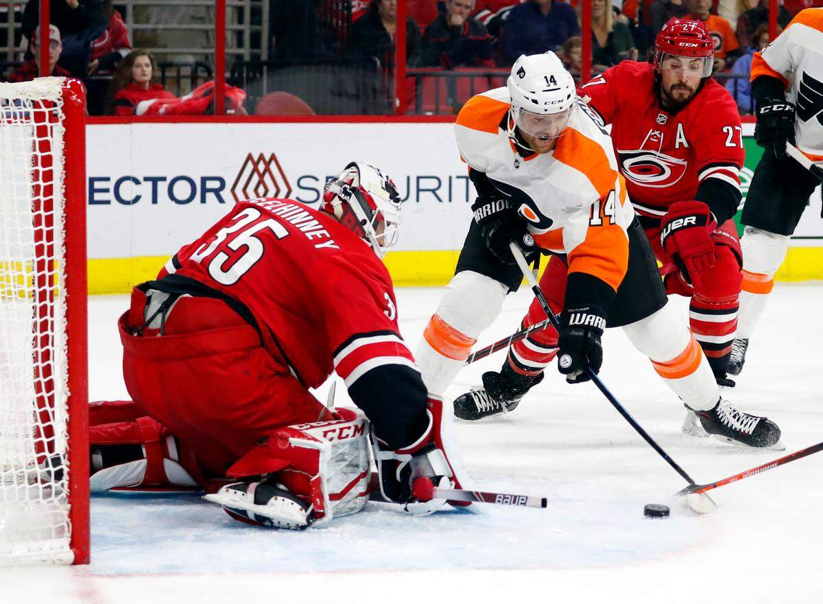 Philadelphia Flyers’ Sean Couturier (14) shoots the puck toward Carolina Hurricanes goaltender Curtis McElhinney (35) during the second period of an NHL hockey game, Monday, Dec. 31, 2018, in Raleigh, N.C. (AP Photo/Karl B DeBlaker)