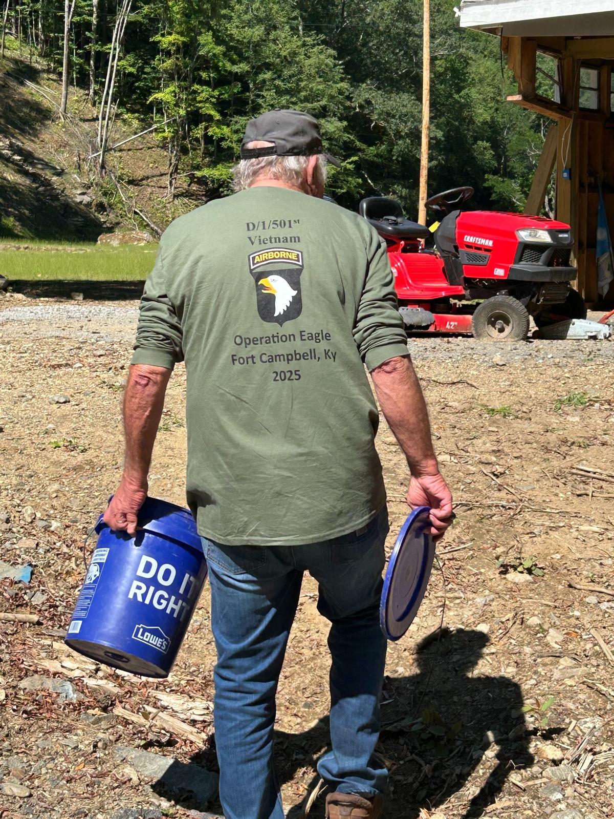 Bob Tatum carries a bucket of trout pellets back from the North Toe River after feeding the fish. Little remains on the Avery County horse farm he and his wife Edwina built over 46 years.