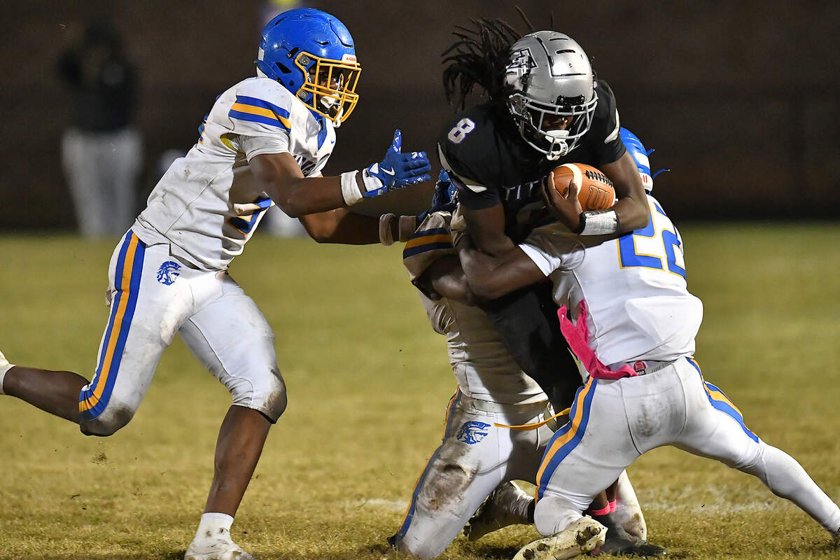 South Garner quarterback Chase Hardy (8) is grappled by  Garner's  Ja'cori Covington (22) during the second half. The South Garner Titans and the Garner Trojans met in a conference football game in Raleigh, N.C. October 17, 2025