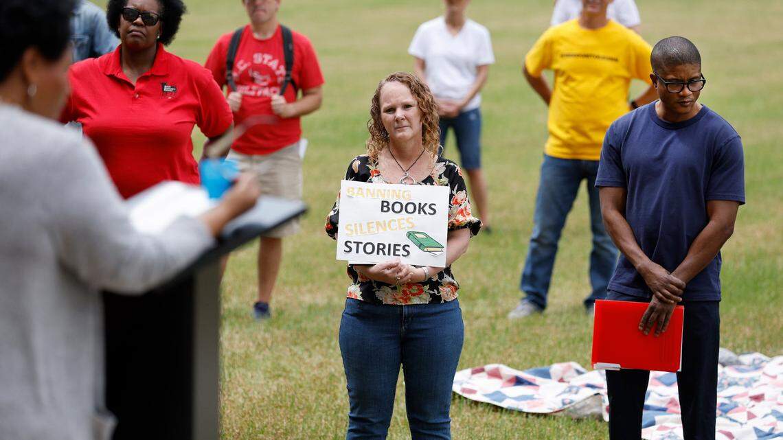 Becky Showalter, center, and William Johnson, right, listen as Janice Robinson reads from The Hate U Give by Angie Thomas during a ‘Celebration of Banned Books’ at Halifax Mall in downtown Raleigh, N.C., Saturday, May 7, 2022.