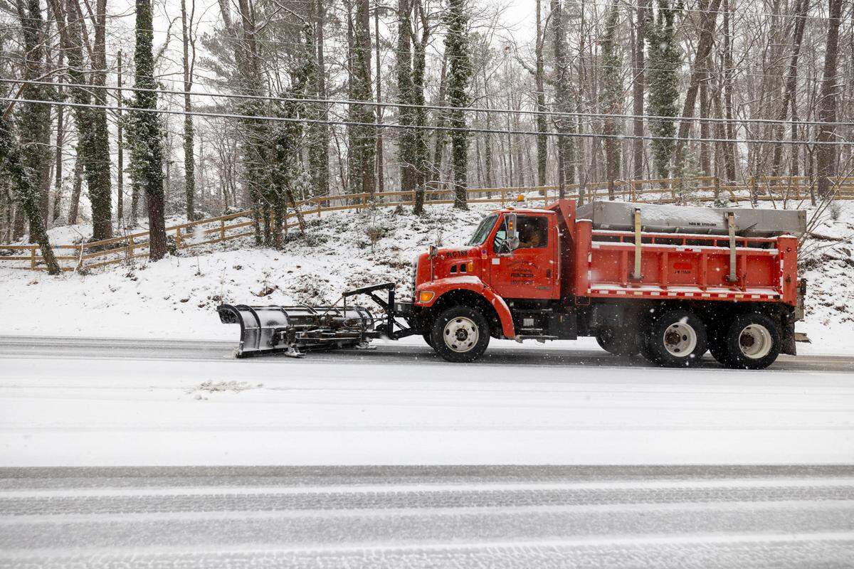 A truck with a snow plow clears a lane of Raleigh Road as a winter storm moves through the area on Wednesday, February 19, 2025 in Chapel Hill, N.C.