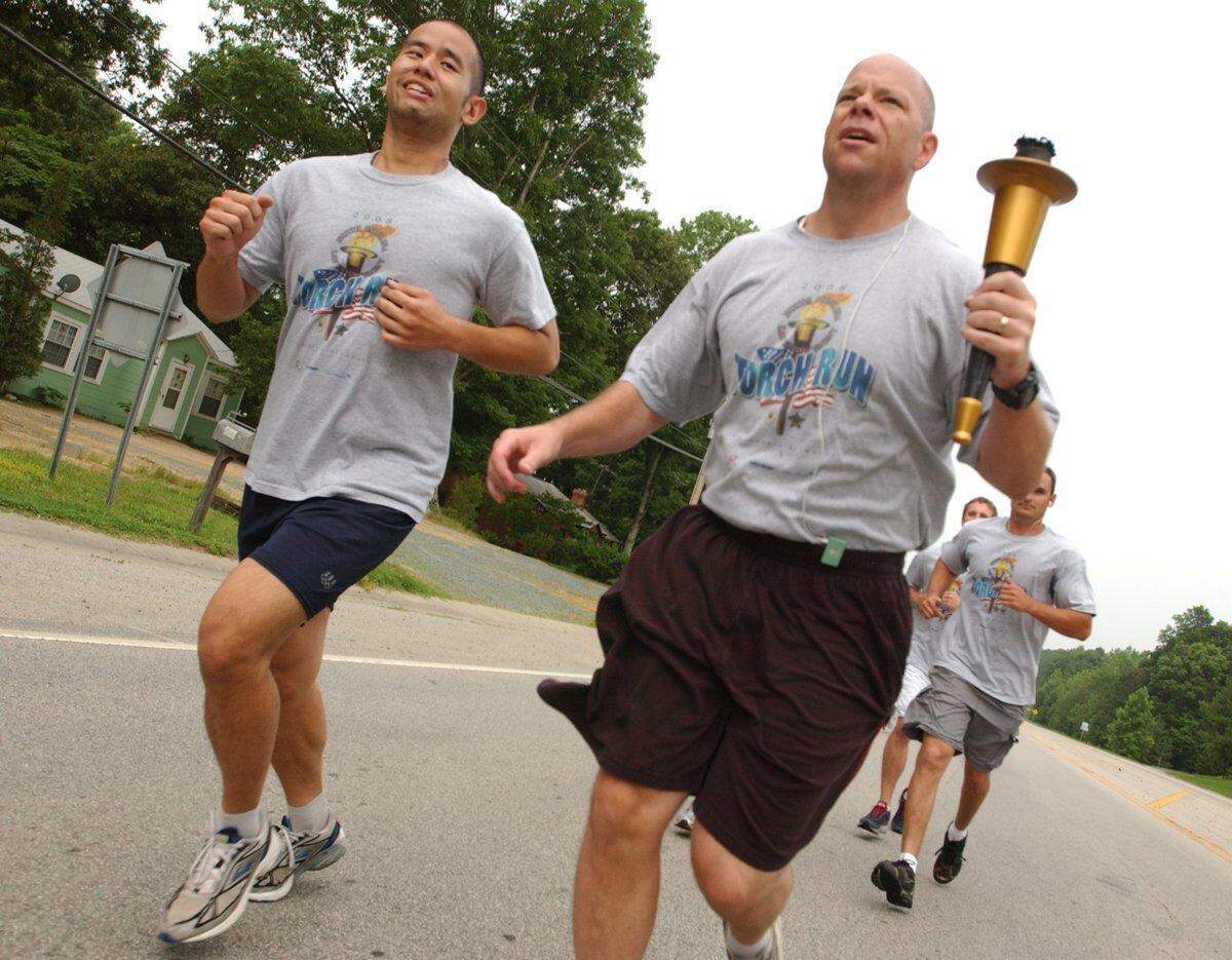 Carrboro fireman Andrew Yu, left, accompanies torch bearer Chapel Hill Police Capt. Chris Blue, right, at the head of the pack of runners during the first leg of the 2008 Orange County Law Enforcement Torch Run For Special Olympics along NC 54 coming into Carrboro.
