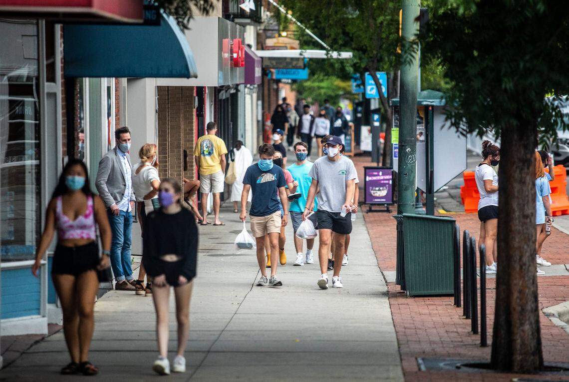 Pedestrians wear masks while walking along Franklin Street in Chapel Hill Thursday, August 7, 2020 amid the coronavirus pandemic.