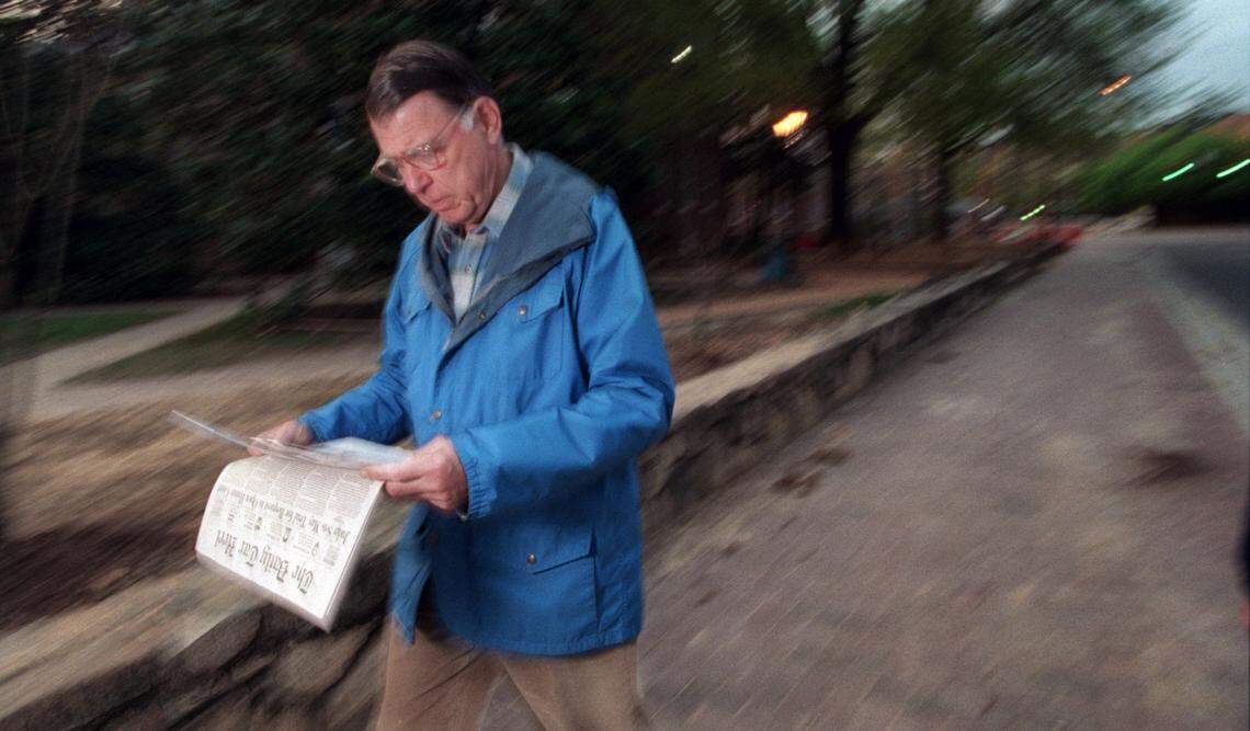 After a morning walk in 1996, UNC system president C.D. Spangler reads the Daily Tar Heel as he cuts across the Chapel Hill  campus to his home. 