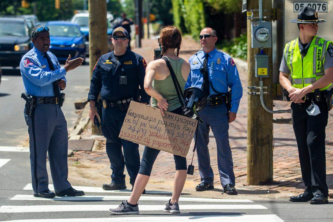 Lindsay Ayling is confronted by police as she counter-protests a group of about a half dozen mostly armed demonstrators affiliated with the Facebook group Blue Igloo as they marched in Downtown Raleigh Saturday, May, 16, 2020.
