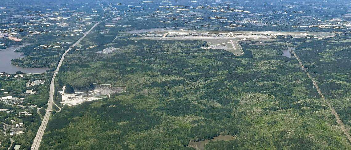 Raleigh-Durham International Airport, top, is seen in this photo taken April 10, 2023. William B. Umstead State Park is in the foreground with Wake Stone Corp’s Triangle Quarry in the middle left.