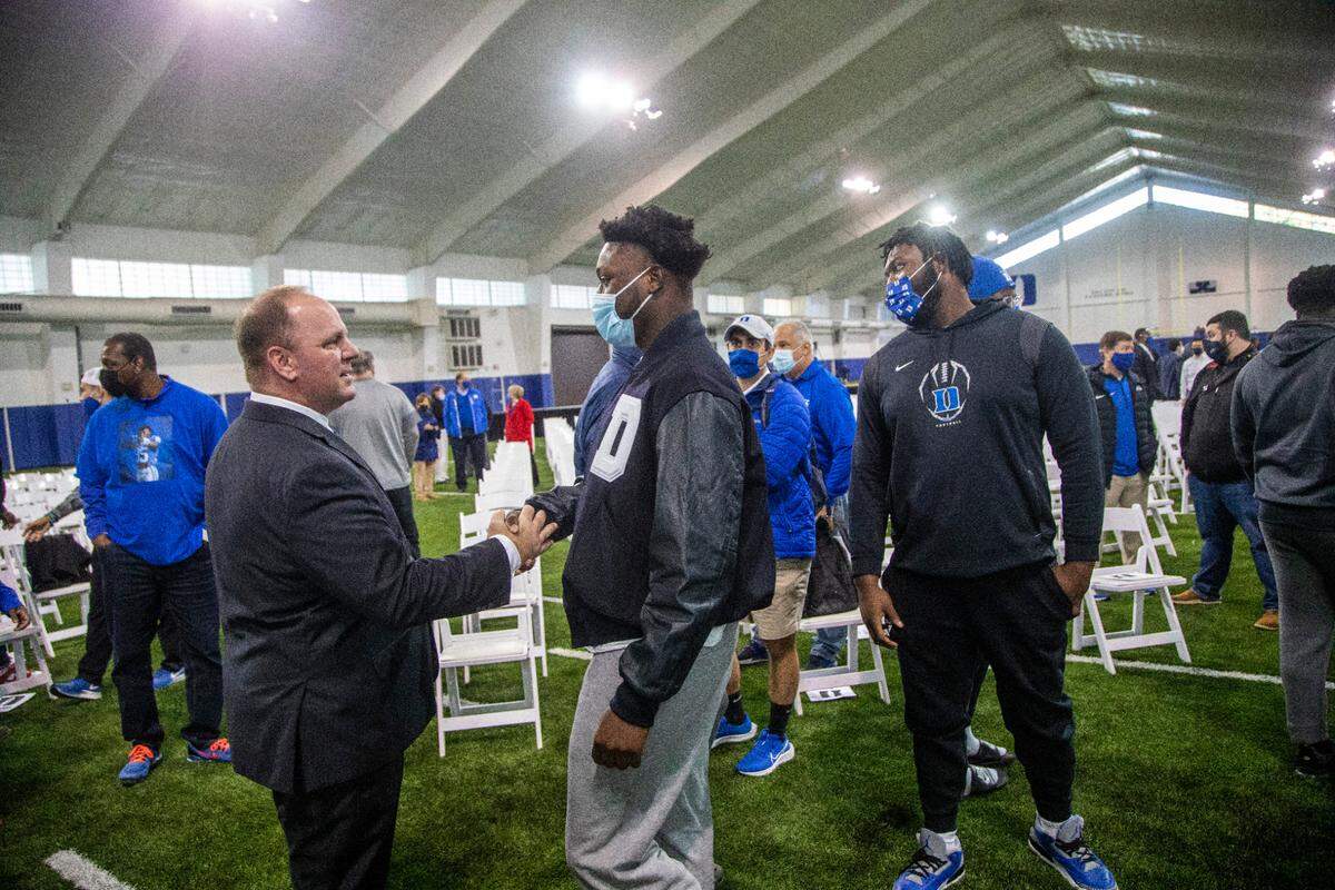 Mike Elko talks with players Caleb Oppan, center, and Peace Addo after being introduced as Duke University’s head football coach during a press conference at Pascal Field House in Durham, Monday, Dec. 13, 2021.