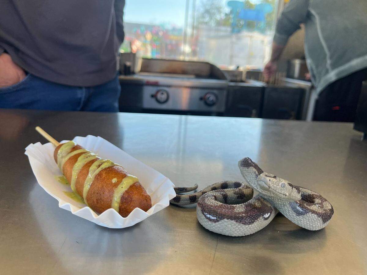 A rattlesnake corndog next to a toy rattelsnake at the Pioneer Wagon food stand at the NC State Fair on Oct. 18, 2022.