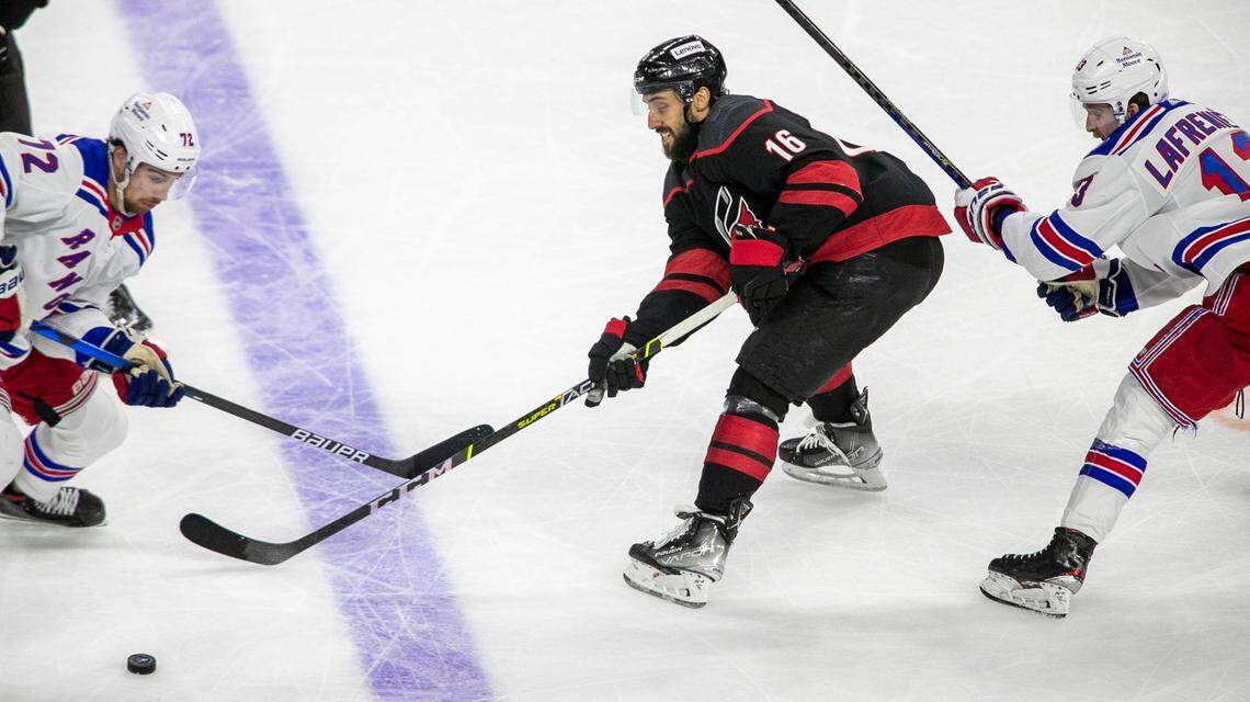 Carolina Hurricanes Vincent Trocheck (16) moves the puck between New York Rangers Alexis Lafreniere (13) and Filip Chytil (72) in the first period on Friday, May 20, 2022 during game two of the Stanley Cup second round at PNC Arena in Raleigh, N.C.