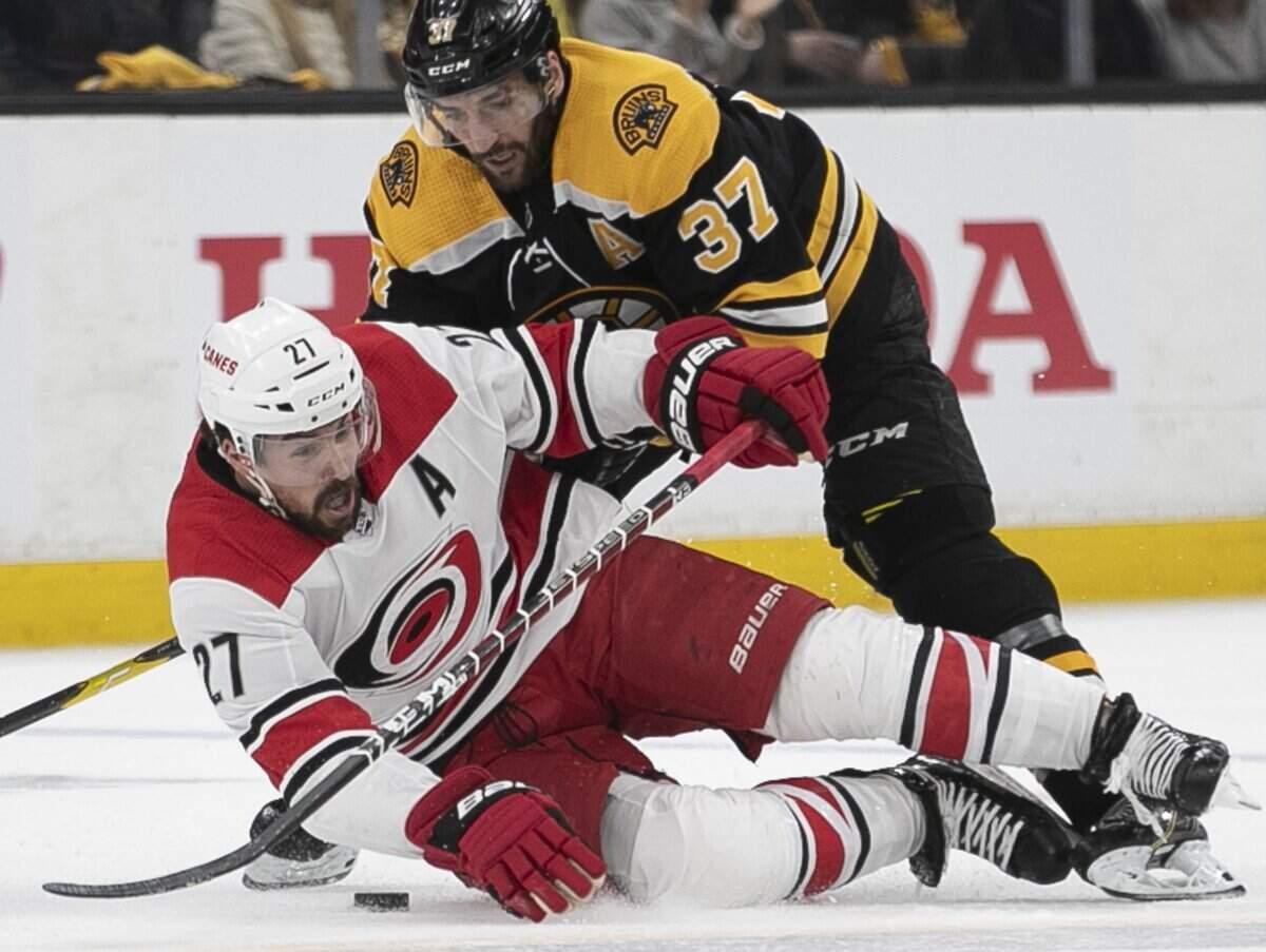 Boston’s Patrice Bergeron (37) checks Carolina Hurricanes’ Justin Faulk (27) to the ice in the first period of Game 2 in the Eastern Conference finals on Sunday, May 12, 2019 at TD Garden in Boston, Mass.