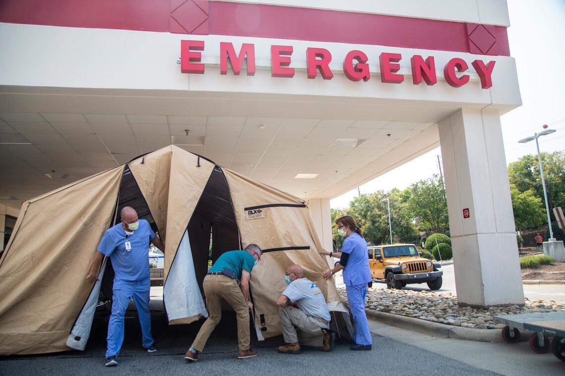 Healthcare and emergency preparedness workers set up triage tents outside the emergency department at UNC REX Hospital in Raleigh Monday, Sept. 13, 2021. The tents will be used to keep up with the volume of patients showing up at the emergency department amid the current COVID-19 surge.