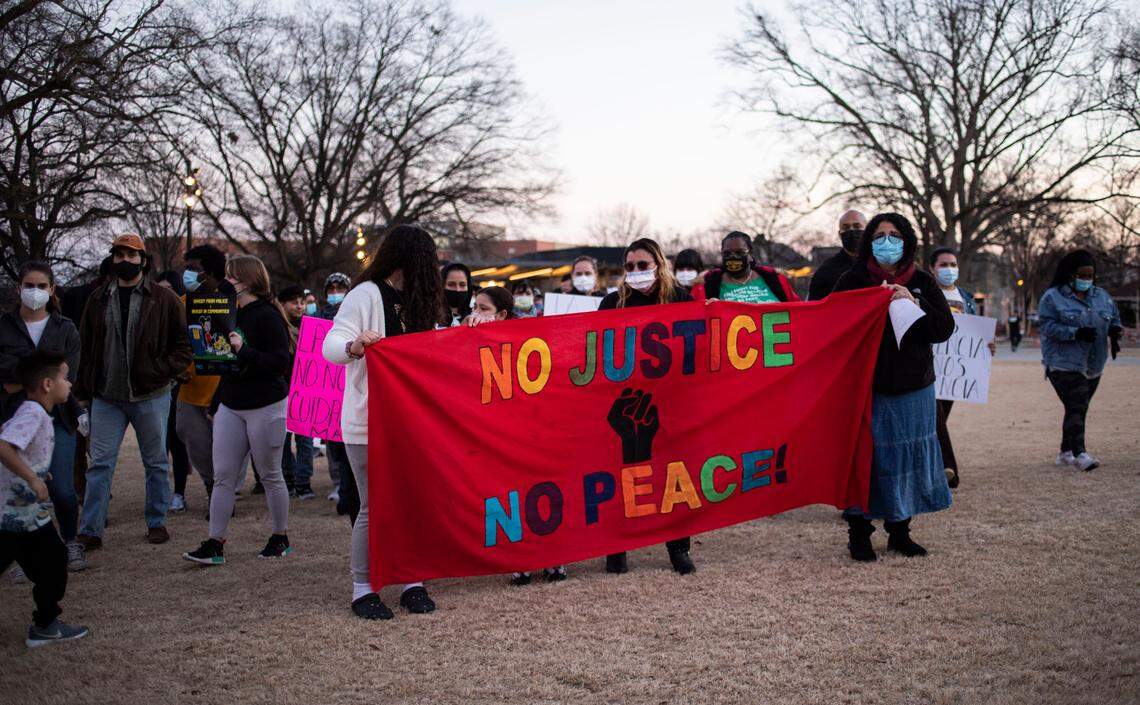Rosa Jerez, middle, stands behind a banner at the start of a downtown Raleigh, N.C. march calling for justice for her husband, Daniel Turcios, who was shot and killed by Raleigh police in January, on Thursday, Feb. 10, 2022.