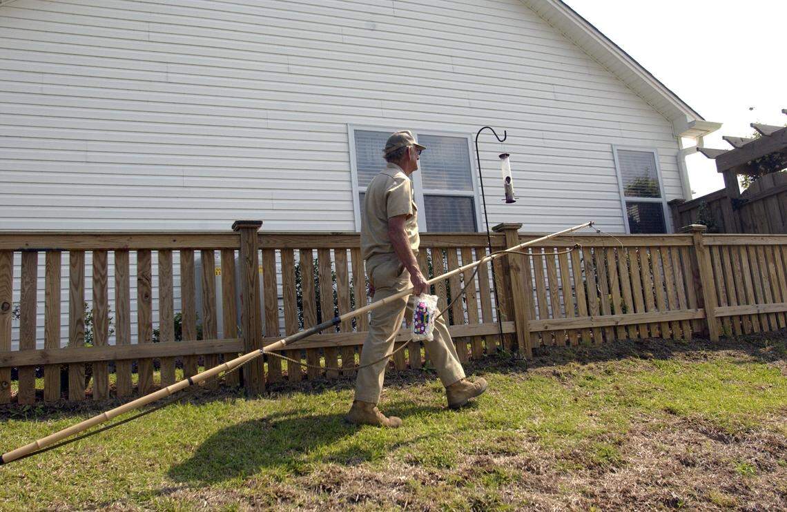 Jimmy English with the tools of his trade — a long cane pole with a noose at the end and a bag of marshmallows. He uses marshmallows to lure the alligators close enough to get the noose around their heads and then reels them in. File photo by John Rottet.