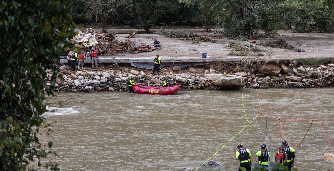 Two people and a dog are escorted to a rescue boat in Chimney Rock, N.C. on Sunday, September 29, 2024.