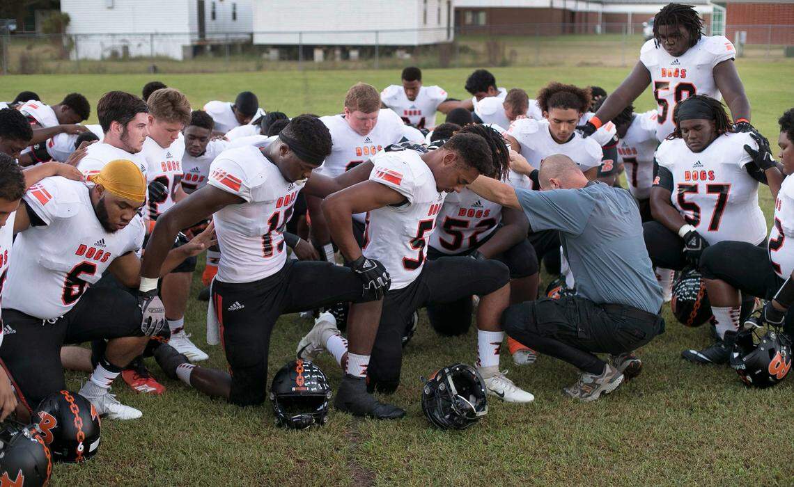 Wallace-Rose Hill coach Kevin Motsinger prays with his players as they prepare to play their first game in nearly a month on Friday, October 5, 2018 in Seven Springs, N.C.