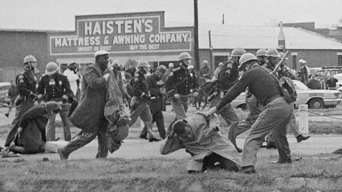 An Alabama state trooper swings a billy club at John Lewis on March 7, 1965, in Selma. Lewis sustained a fractured skull. (AP)