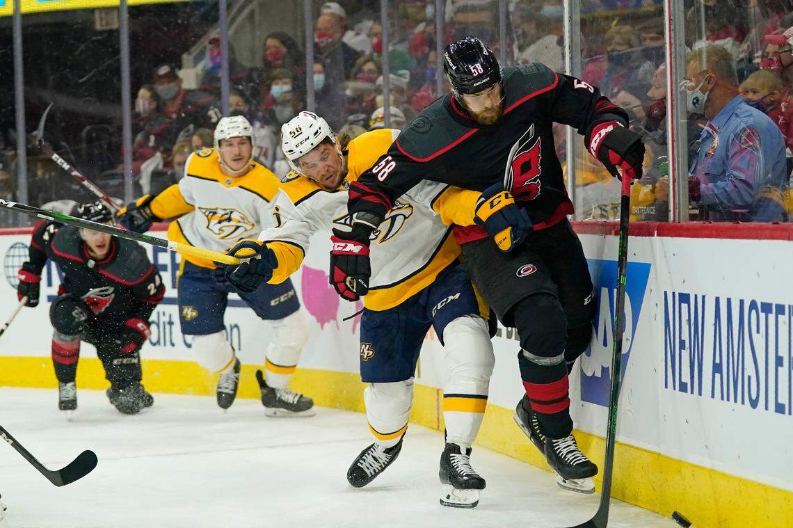 Nashville Predators left wing Erik Haula (56) and Carolina Hurricanes defenseman Jani Hakanpaa (58) chase the puck during the first period in Game 1 of an NHL hockey Stanley Cup first-round playoff series in Raleigh, N.C., Monday, May 17, 2021. (AP Photo/Gerry Broome)