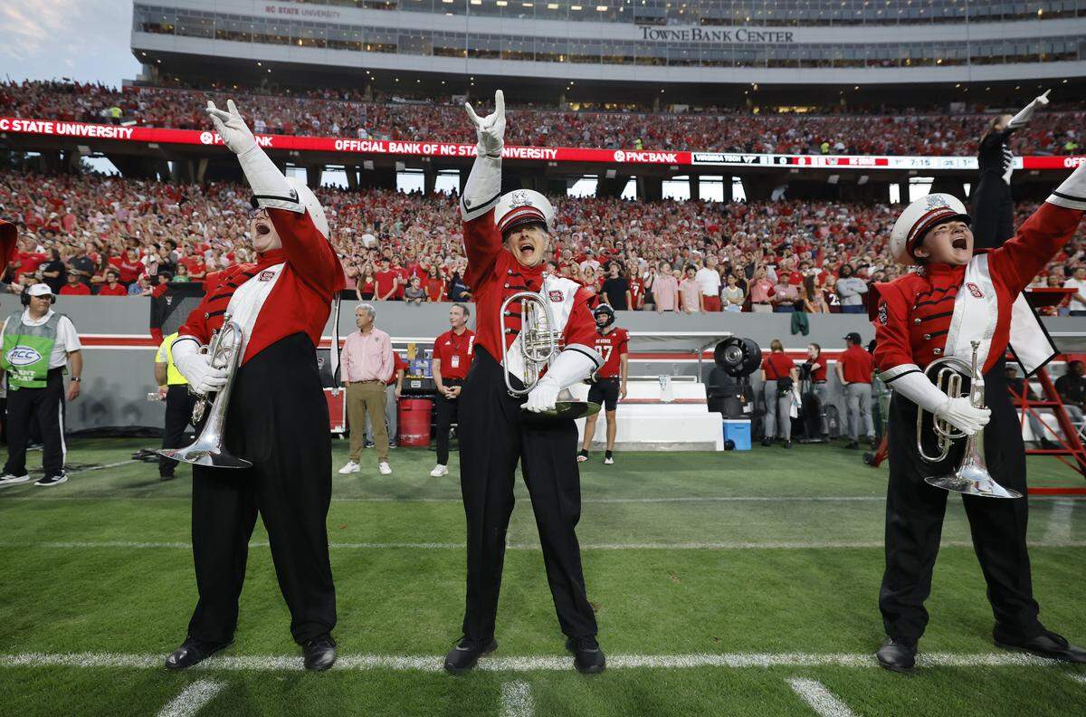 N.C. State Marching Band member Lois Roegge, 58, center, cheers with the band after marching out onto the field before N.C. State’s game against Virginia Tech at Carter-Finley Stadium in Raleigh, N.C., Saturday, Sept. 27, 2025.