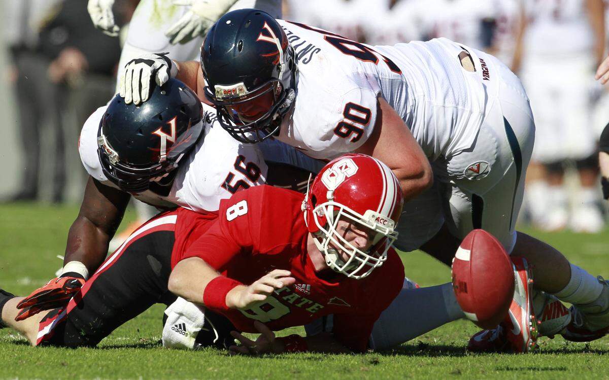 N.C. State quarterback Mike Glennon (8) fumbles the ball after being sacked by Virginia defensive tackle Chris Brathwaite (56) and defensive end Jake Snyder (90) during their game on November 3, 2012. Virginia, near the bottom of the league at the time, soundly beat the Wolfpack after the Pack pulled a stunning upset of Top-10 ranked Florida State Univ. a few weeks earlier.