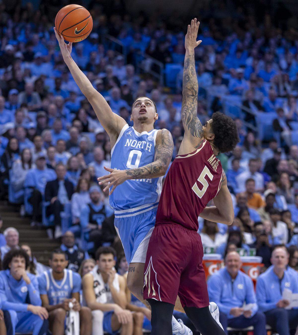 North Carolina guard Kyan Evans (0) drives to the basket against Florida State forward Kobe Magee (5) in the second half on Tuesday, December 30, 2025 at the Smith Center in Chapel Hill, N.C. Evans scored 15 points in the Tar Heels’ victory.