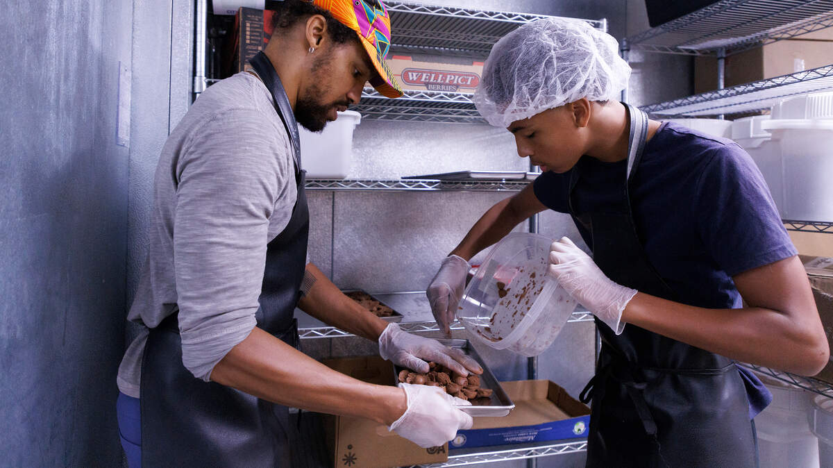 Pierce Freelon and his son, Justice, 15, work to arrange mini ice cream scoops on trays before transferring them to a freeze dryer at Piedmont Food Processing Center in Hillsborough, N.C. on Tuesday, June 4, 2024. Freelon produces Coco Fro, vegan freeze-dried ice cream.