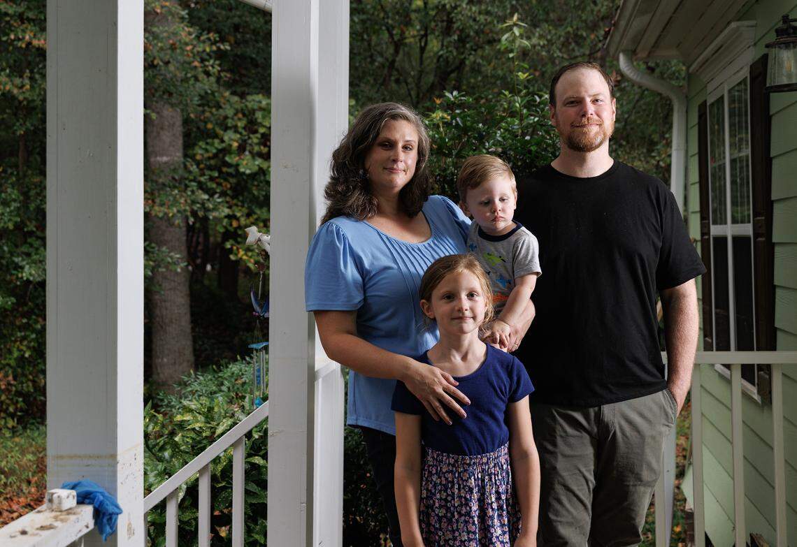 Rebecca and Ryan Blough pose for a portrait with their children, Emma, 7, and Henry, 1, on the porch of their Pittsboro home, which was severely damaged by flooding during Tropical Storm Chantal.