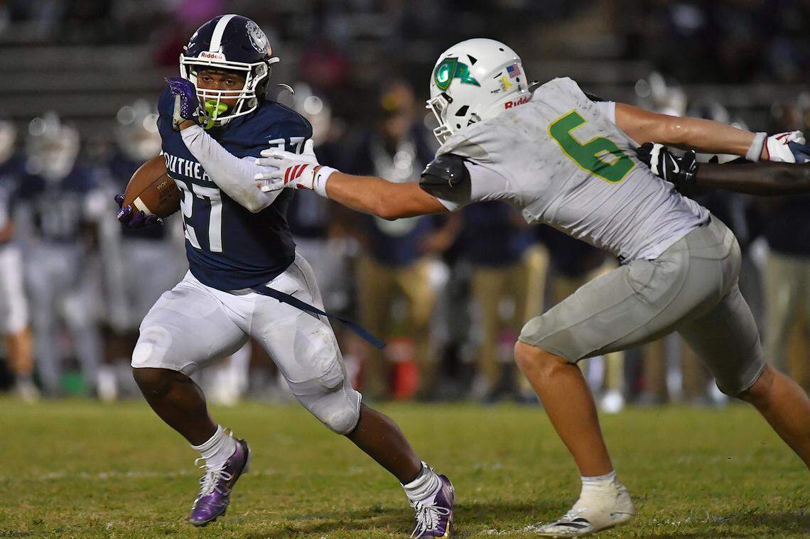 Southeast Raleigh running back James Adams IV (27) runs for yardage against Cardinal Gibbons defensive end 	Griffin Cockerham (6) during the first half. The Southeast Raleigh Bulldogs and the Cardinal Gibbons Crusaders met in a non-conference football game in Raleigh, N.C. September 12, 2025