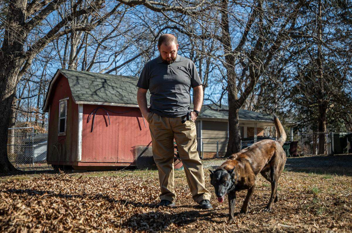 William Carson and his dog Tap, both former Durham County sheriff’s employees, walk through a family member’s yard in Durham, N.C. on Thursday, Jan. 27, 2022.