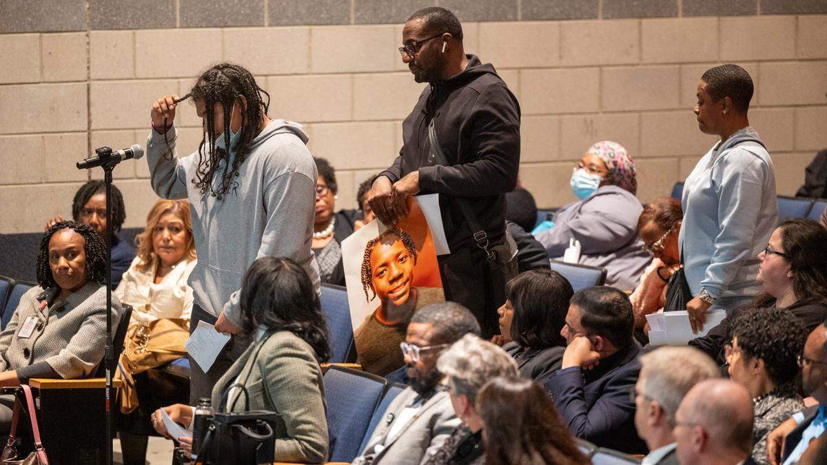 Delvin Ferrell’s older brother Jeremaine Cotton, left, speaks as Ferrell’s uncle Teddie Martinez olds a portrait of Ferrell during a community forum at Southeast Raleigh High School Monday, Dec. 4, 2023, one week after a brawl resulted in the fatal stabbing of a 15-year-old student and the wounding of a 16-year-old.