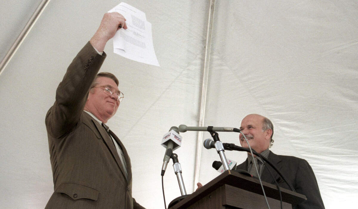 Steve Stroud of the Centennial Authority holds up a document of intent after he and Hartford Whalers owner Peter Karmanos (right) signed it at festivities celebrating the announcement in 1997