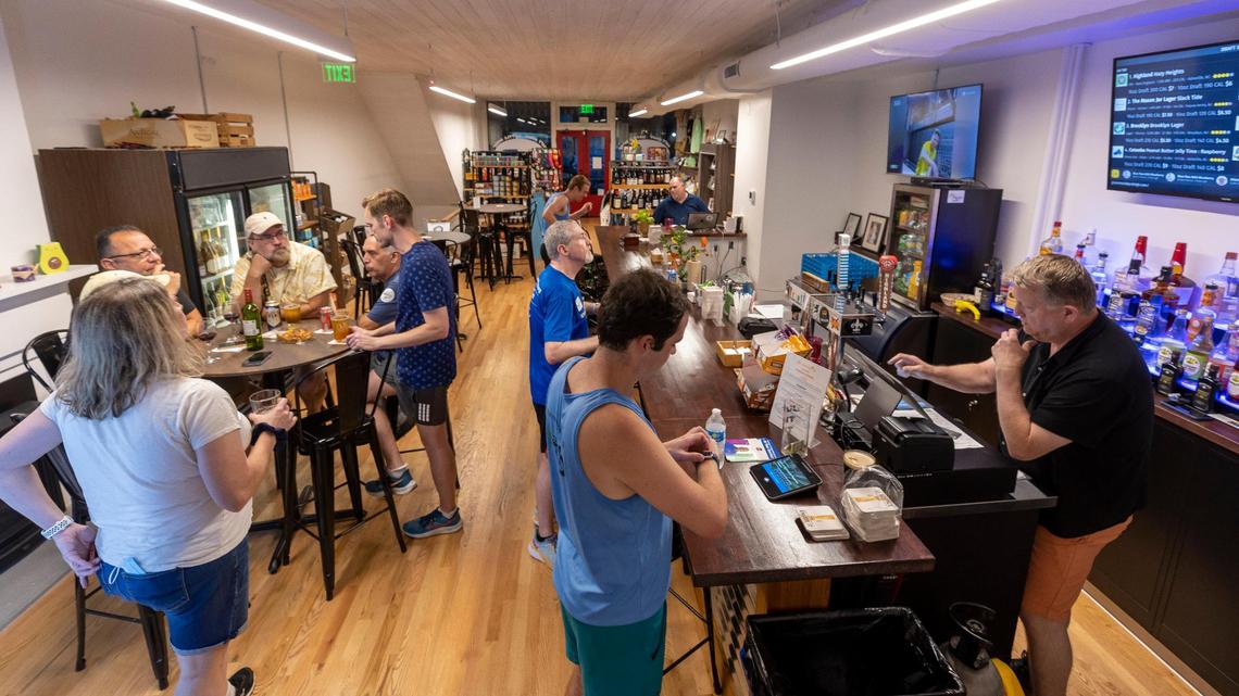 Drew Temple, right, serves customers at The Green Monkey bar on Tuesday, September 12, 2023 in Raleigh, N.C. The gift shop, bottle shop and neighborhood bar has relocated from Hillsborough Street into a new space at 215 S. Wilmington Street.