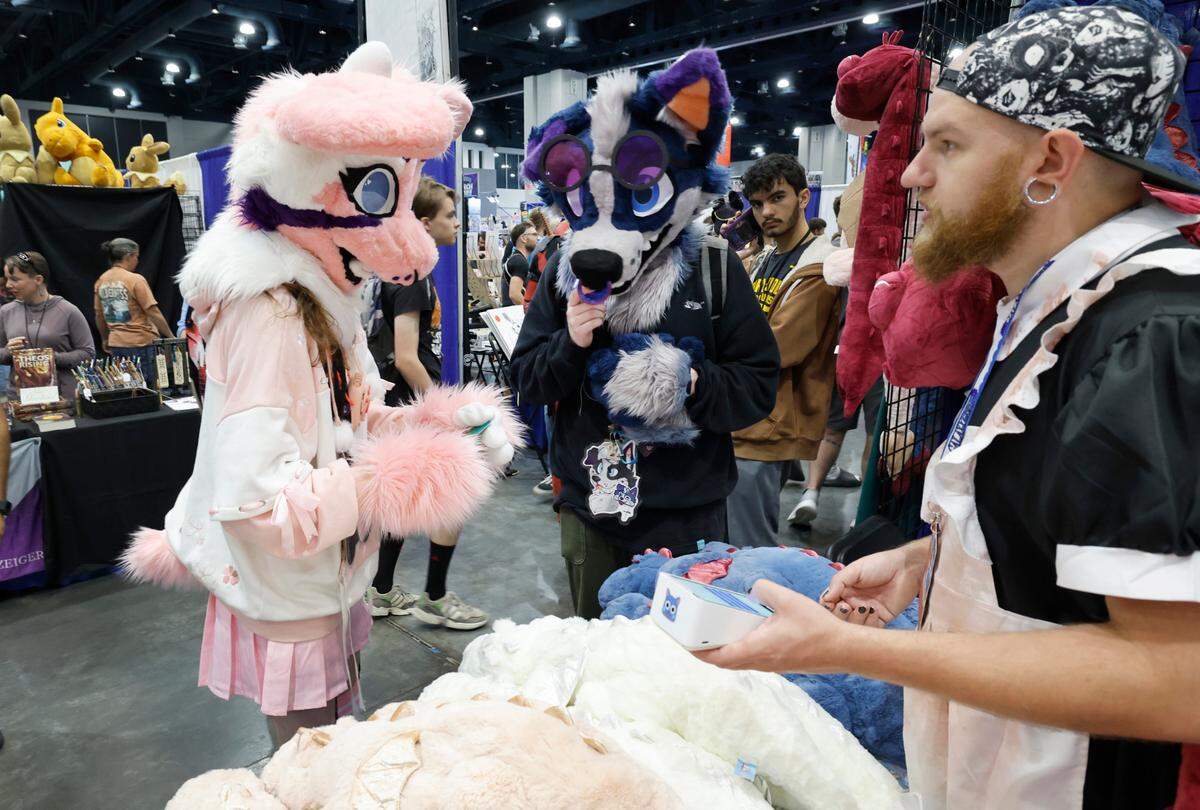 Milo Denote of Wilmington, left, and Brayden Dyson of Whiteville, center, shop at White Tiger Collectables at GalaxyCon Raleigh at the Raleigh Convention Center Sunday, July 28, 2024.