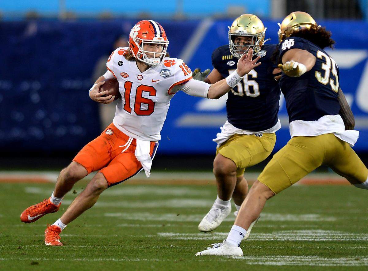 Clemson Tigers quarterback Trevor Lawrence, left, rushes for yardage against the Notre Dame defense during second quarter action at Bank of America Stadium on Saturday, December 19, 2020 in Charlotte, NC. The Clemson Tigers and Notre Dame Fighting Irish faced off in the ACC Championship game.