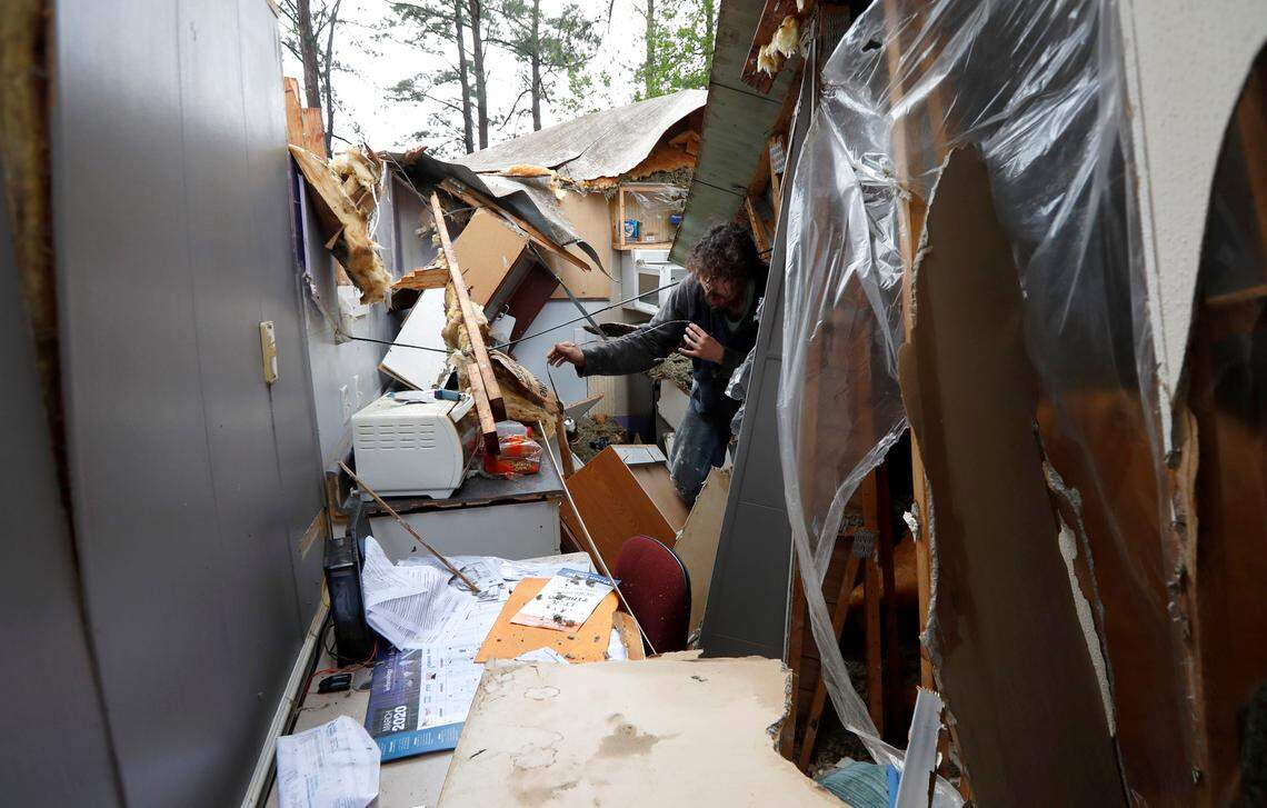 Jacob Aliff helps his father, Michael, salvage items after a tree hit their home in Lakeview Mobile Estates south of Raleigh Monday morning, April 13, 2020. Michael Aliff, who has owned the trailer for 35 years, said he was sitting in his chair in the living room around 7:50 a.m when, without warning, “all hell broke loose.” He was uninjured.