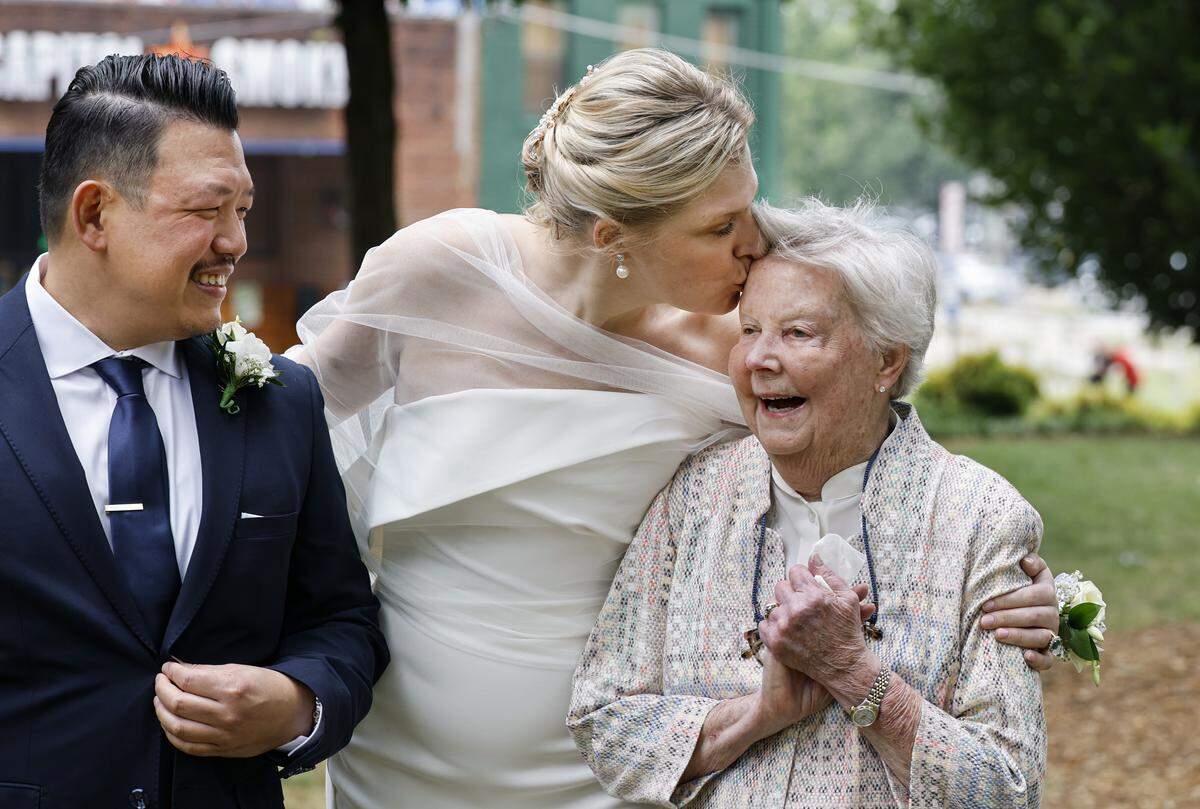 Rebecca Stewart kisses her grandmother, Janice Rockett, after Stewart married Billy Khantawong, left, in Nash Square Park in Raleigh, N.C., Friday, May 22, 2026.