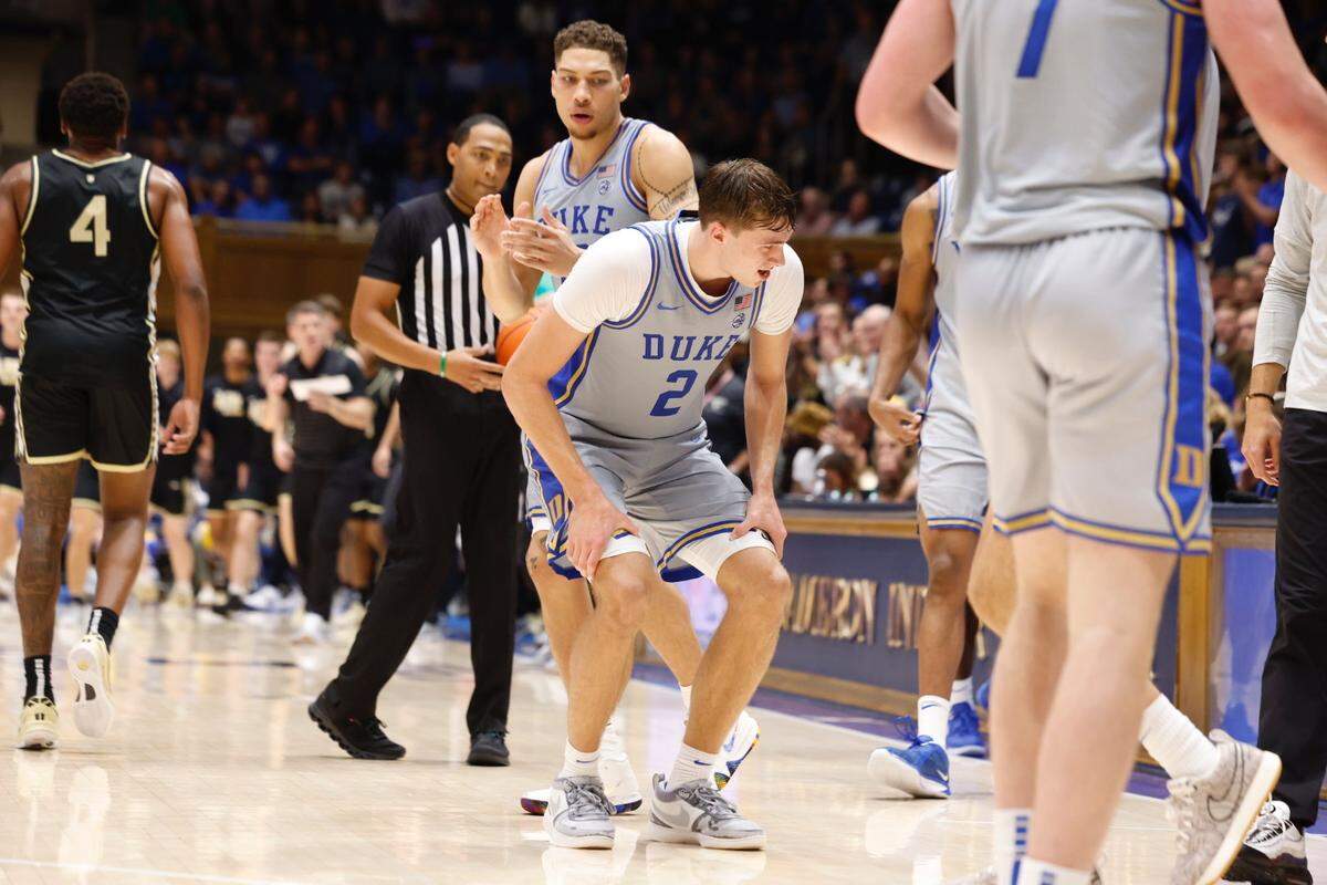 Cooper Flagg holds his legs as he comes off the court. Flagg would leave the bench area before returning