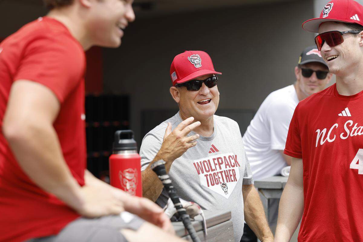 N.C. State head baseball coach Elliott Avent laughs with his players including Jacob Dudan (41), right, during practice at Doak Field Tuesday, May 26, 2026.