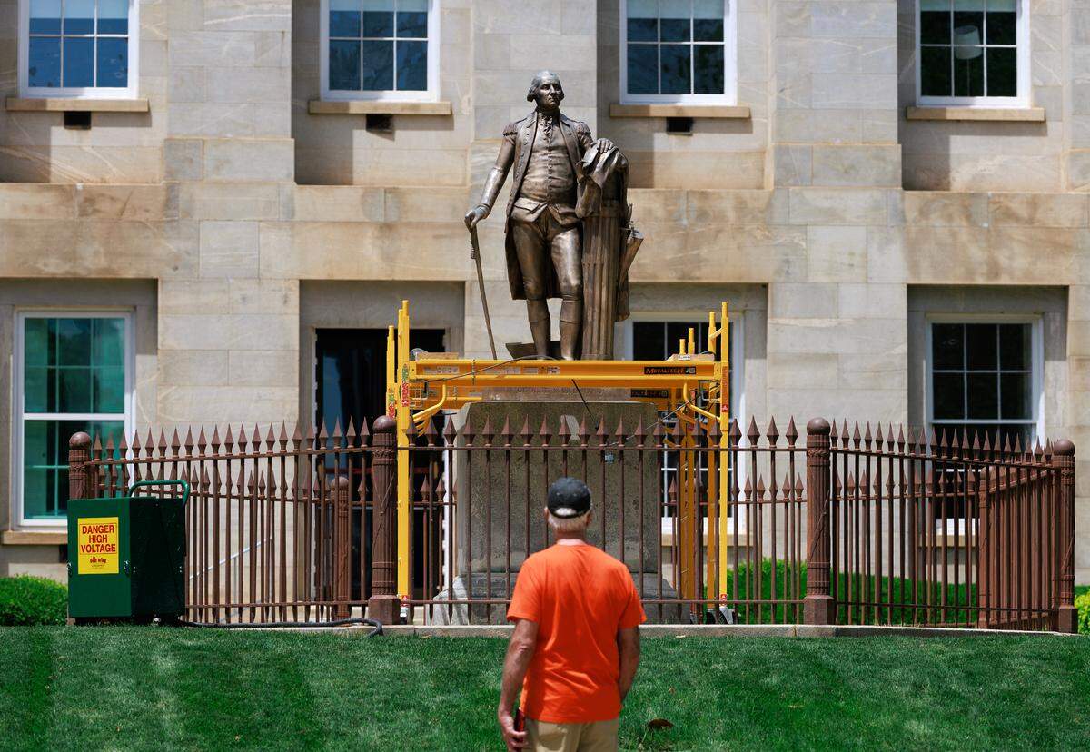 A visitor eyes the statue of George Washington on the grounds of the North Carolina State Capitol in Raleigh.