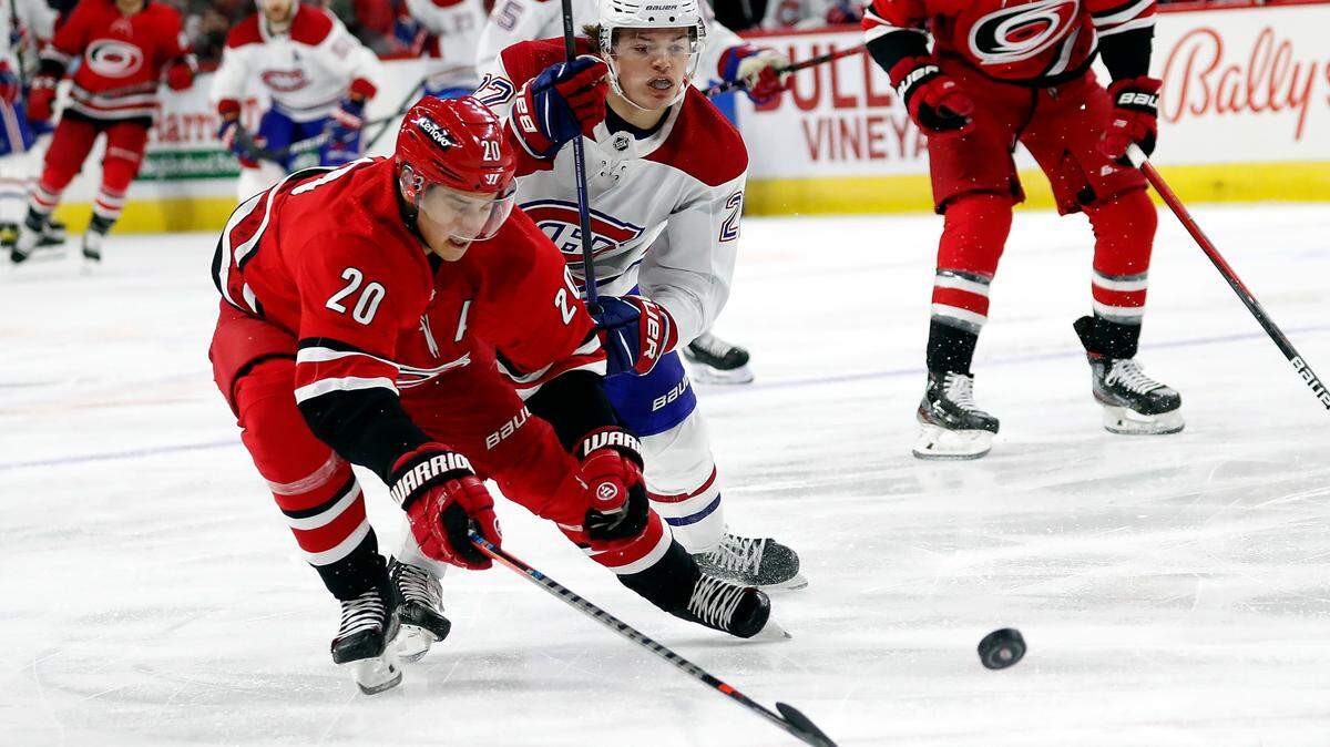 Carolina Hurricanes’ Sebastian Aho (20) tips the puck away from a charging Montreal Canadiens’ Cole Caufield (22) during the first period of an NHL hockey game in Raleigh, N.C., Thursday, Dec. 30, 2021. (AP Photo/Karl B DeBlaker)