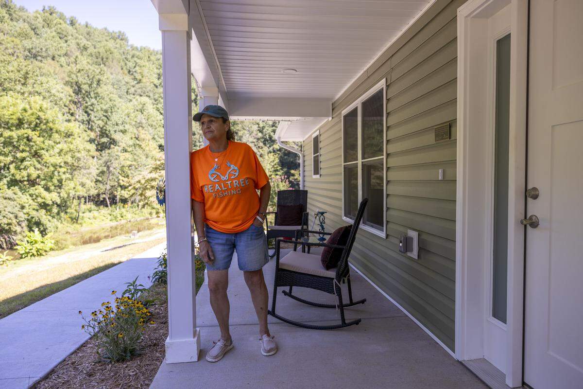 Lisa Thomas stands on the porch of her new home, built on higher ground by Samaritan’s Purse, in Spruce Pine on Aug. 29 — nearly a year after flooding and a landslide from the remnants of Hurricane Helene destroyed her home.