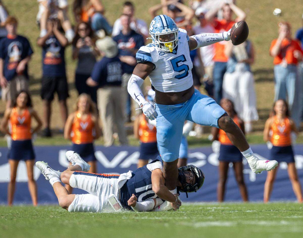North Carolina defensive lineman Jahvaree Ritzie (5) breaks away from a tackle by Virginia quarterback Anthony Colandrea (10) after intercepting his pass, returning it 84-yards for a touchdown in the third quarter to give the Tar Heels’ a 38-6 lead on Saturday, October 26, 2024 at Scott Stadium in Charlottesville, Va.