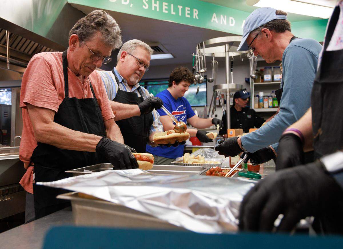 Erik Van Ooijen, left, works with a team of volunteers to prepare meatball subs for dinner at Urban Ministries of Durham’s community cafe on Wednesday, May 14, 2025.