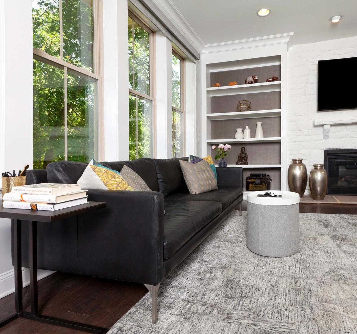 Contrast and visual interest was created in this modern, monochromatic living space by adding black and white elements throughout as well as different hues of grey and mixed metal finishes.